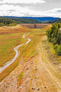 A narrow river runs through the valley with a dam and meadows, rehabilitation of the Schwarzenbach