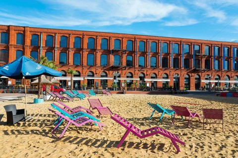 Colourful deckchairs on sand in front of a long brick building, Manufaktura, Lódz, Lodz, Lodz,