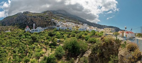 Idyllic village of Mesochori on a mountainside under a dramatic cloudy sky with white architecture,
