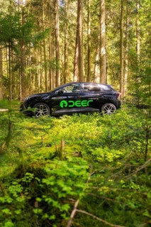 Vehicle with green logo parked in a shady wooded area, Deer E- Carsharing, Calw, Black Forest,