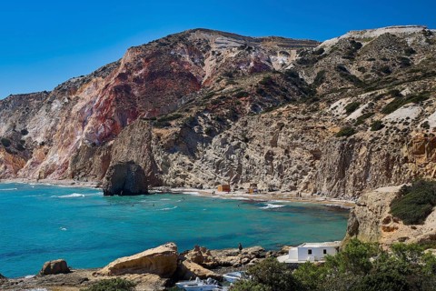 Beach, volcanic rock, panoramic view of a coastal bay with rocks, residential buildings and blue