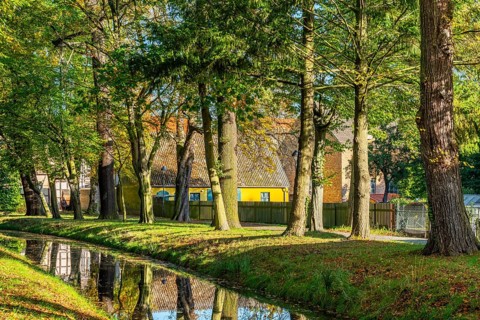 Autumn coloured trees in a park at the river Nieplitz, behind a yellow farmhouse, Treuenbrietzen,