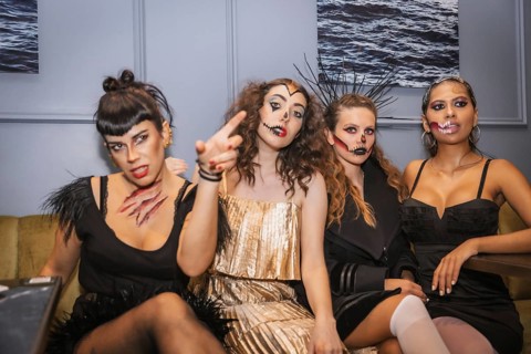 Halloween party with friends in a disco nightclub, portrait of a group of female friends sitting on
