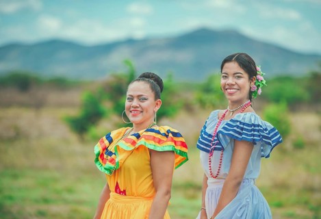 Two smiling Hispanic girls wearing cultural folkloric costumes outdoors. Portrait of two Hispanic