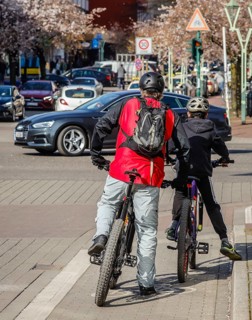 Cyclists waiting on the cycle path at a traffic light crossing to continue their journey on