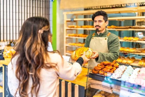 Rear view of a female elegant client buying bread in an artisan bakery shop