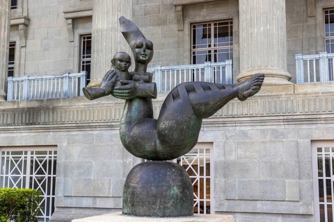Mother and Child sculpture, a stylised bronze figure by sculptor Ng Eng Teng cradles a child before