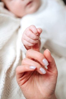 A close-up image capturing a tender moment as a mother gently holds her newborn baby girl's tiny