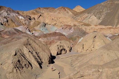 A hiker in a narrow gorge with colorful rock walls in the desert, Artist Drive, Death Valley