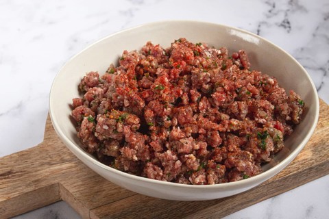 Raw minced meat, marinated with spices and herbs, in a bowl, minced meat with spices, top view,