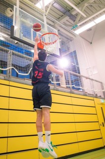 Player jumps for a dunk in a basketball game in front of a yellow wall, basketball TSV Calw,