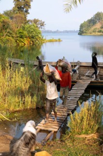 Rwandan men carry sandbags on their heads from a wooden boat to the shores of Lake Kivu or Lake