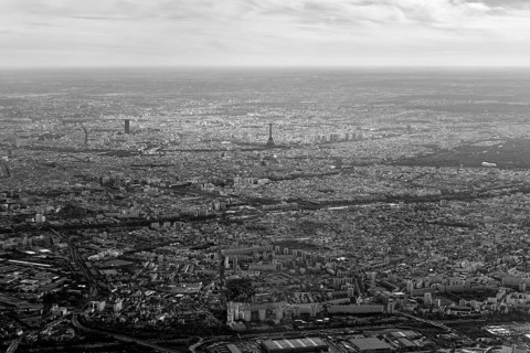 Black and white aerial view of an extensive cityscape under a cloudy sky, flight, aerial view