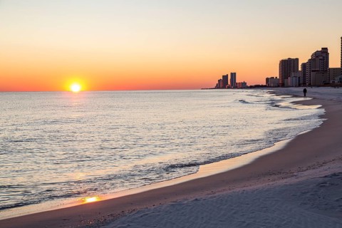 Man walking on the beach at sunset in Gulf Shores, Alabama