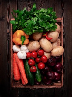 Assortment of vegetables, in a wooden food box, on a wooden table, top view, no people