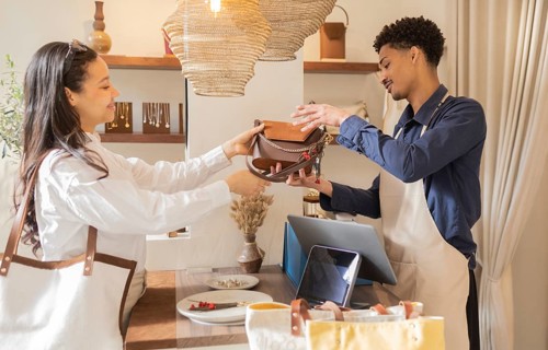 A customer and shop assistant exchanging a handbag in a boutique store. The shop offers a range of