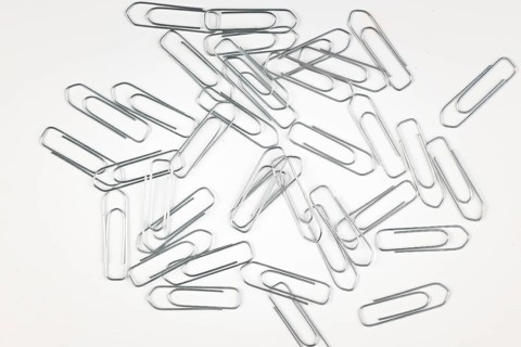 Lots of silver paper clips on a white background