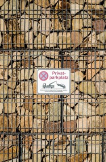 Sign on a gabion filled with stones, German for private car parking, Germany