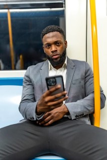 Young businessman commuting on a subway train, using a smartphone to check messages and browse