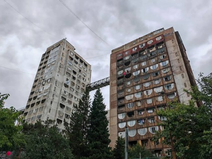 Two tall residential buildings with a bridge as a connection in a dramatic atmosphere in a wooded
