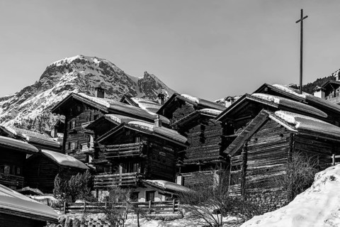 Snow-covered old farmhouses, large wooden cross, black and white photo, historic town center,