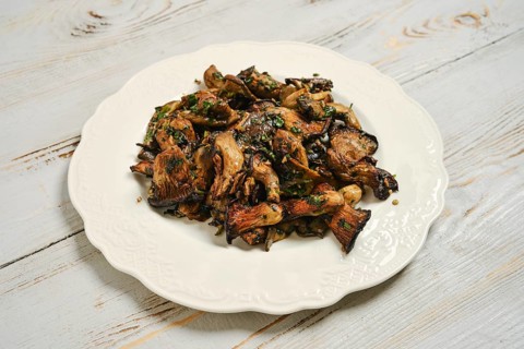 Oyster mushrooms cooked in air fryer served on white plate on wooden table