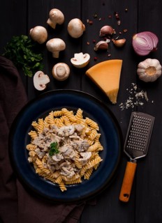 Fusilli pasta, with champignons in cream sauce, top view, with ingredients, on a wooden table, no