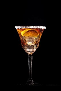 A cocktail glass with lemon slices and ice cube cubes against a black background