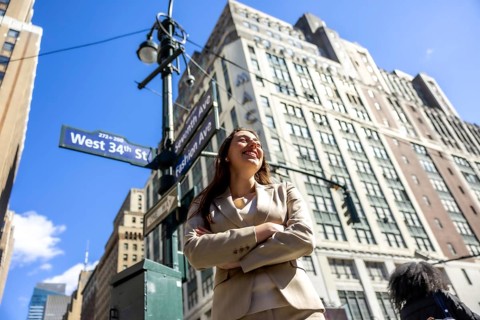 Confident businesswoman standing with arms crossed, smiling brightly while looking up against a