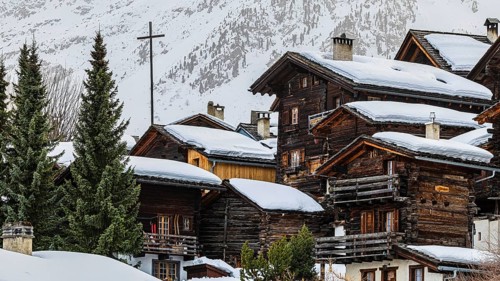 Snow-covered old farmhouses, large wooden cross, historic town center, Grimentz, Val d'Anniviers,