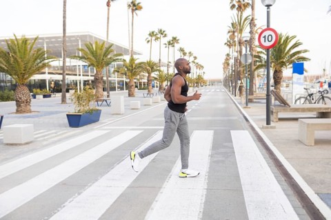 A cuban man jogs on a palm lined avenue, incorporating fitness into his lifestyle. The inviting