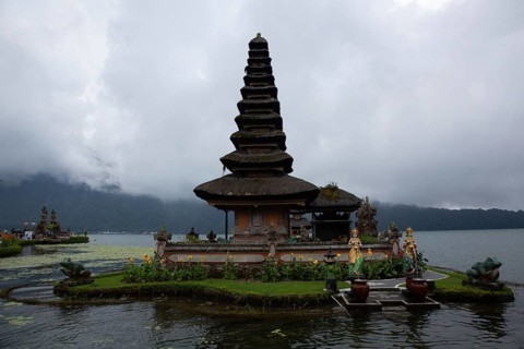 Traditional temple in Bali on a small island surrounded by calm water and clouds, Buddhist water