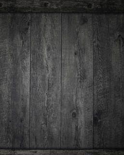 A textured background featuring dark wooden planks arranged horizontally, showcasing natural grain