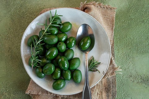 Chalkidiki olives, classic Greek green olive, on a plate, with a spoon, top view, no people