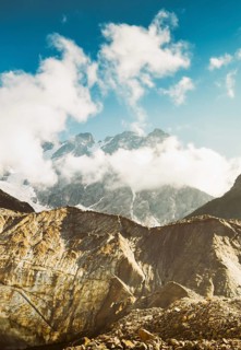 Georgia Svaneti Shkhara glacier summer morning with clouds drift across rugged peaks, moraine rocks