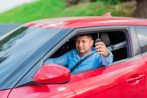Happy driver showing car key. Male driver showing his car keys