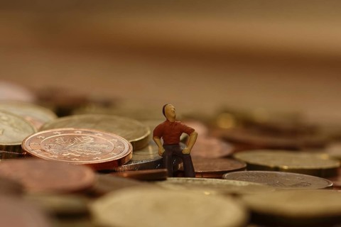 Miniature man sitting among euro coins, North Rhine-Westphalia, Germany