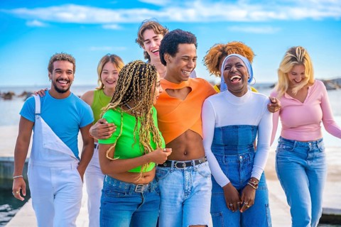 Frontal view of a happy transgender person and multi-ethnic friends embracing while walking along a