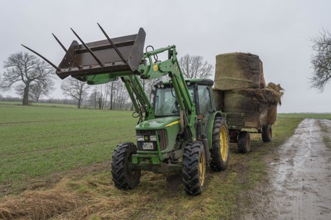 Tractor and loader wagon loaded with old hay bales, Mecklenburg-Vorpommern, Germany