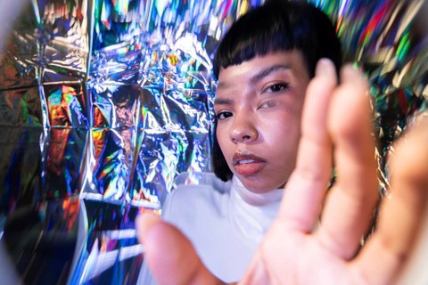 A futuristic Latin woman explores the vibrant metaverse, surrounded by a spectrum of holographic