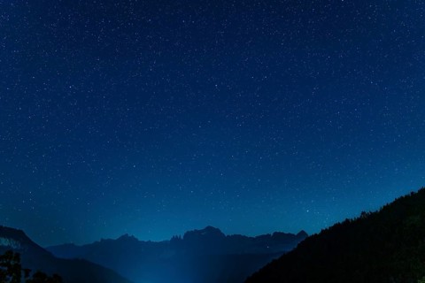 Breathtaking view of a majestic night sky filled with twinkling stars illuminating a dark mountain