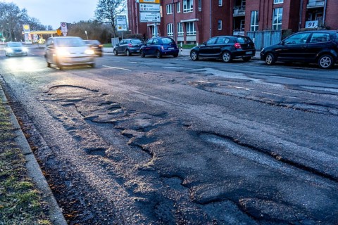 Many large potholes on an inner-city road, Lange Straße in Krefeld-Uerdingen, the heavily