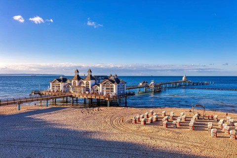 Historic pier with pavilion over the sea and beach chairs on the sandy beach, Rügen, Sellin