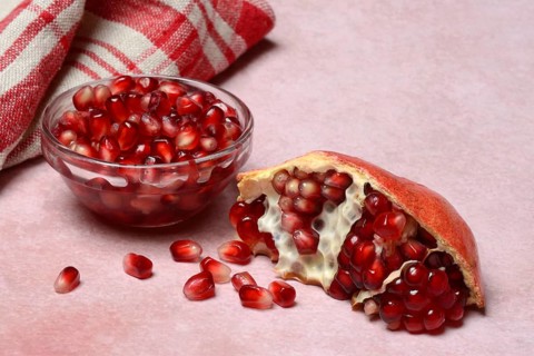 Opened pomegranate and pomegranate seeds in skin, Punica granatum