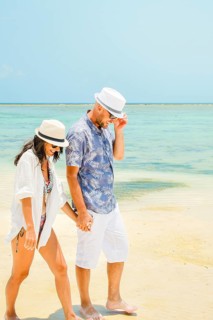Happy caucasian couple enjoy walk on tropical holiday vacation together having fun on sunny beach.