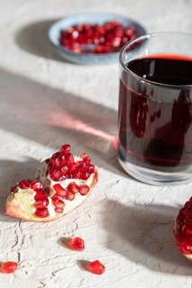 Glass of pomegranate juice on a white concrete background. Hard light, contrast. Side view, close
