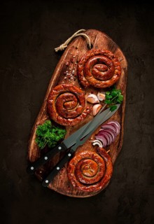 Fried spiral sausages, on a wooden board, top view, with spices, no people