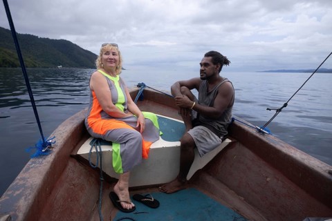 A mature female tourist and a native man share a scenic boat tour around Kri Island, in the
