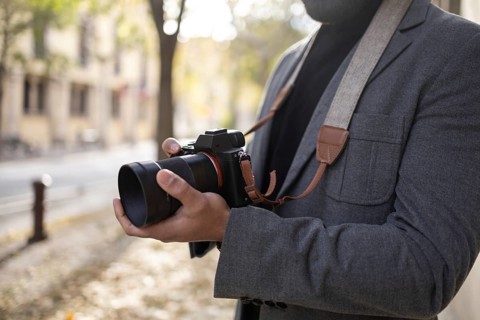 Cropped unrecognizable man, dressed as a photographer with a stylish gray jacket and a camera
