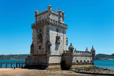 Old fortress jutting into a river, with sandy beach and blue sky, Torre de Belém, World Heritage